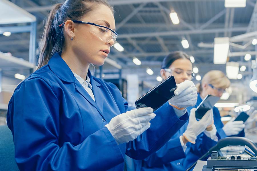 A team of women wearing blue lab coats and gloves in a quality control laboratory