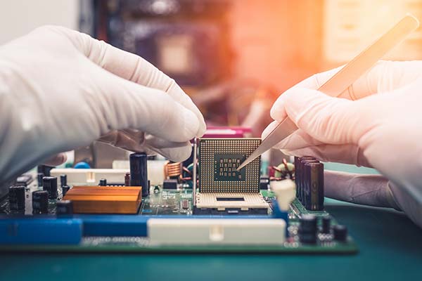 Gloved hands working on a computer chip for quality control