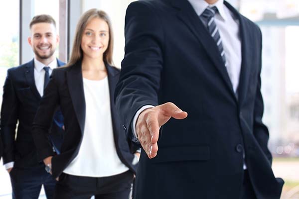 A business professional reaching out for a handshake in a corporate meeting